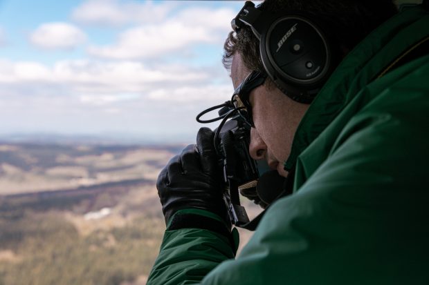 A member of the FC PLant Health Forestry Team in a helicopter undertaking am aerial survey