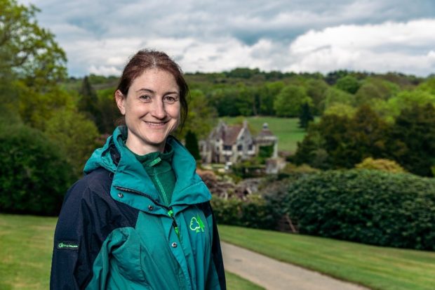 A woman wearing a forestry commission coat smiles at the camara