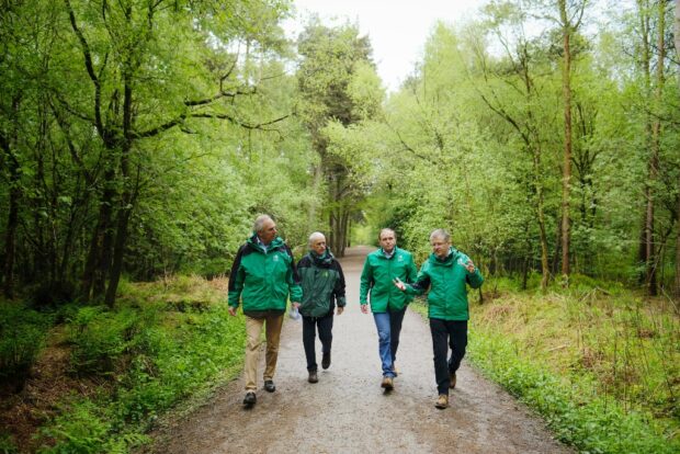 Four men walk through a woodland