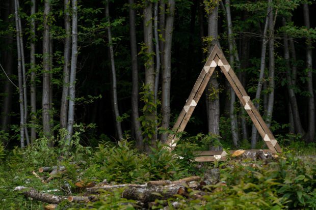A large wooden triangle with a backdrop of trees