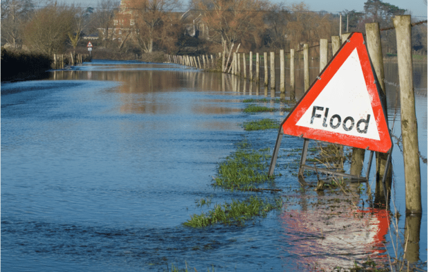 A flooded field with a red wornding sign saying Flood in it