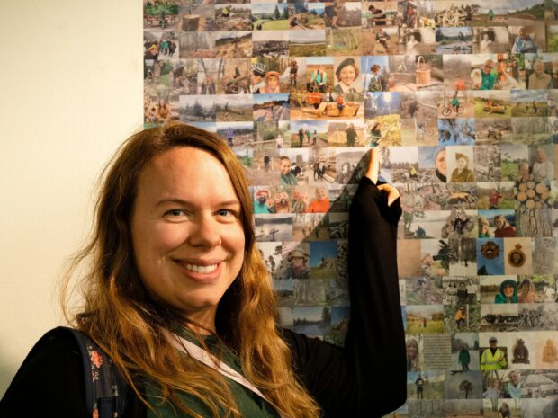 Kate Hawley looks at the camara whilst pointing to her image which is part of the bigger People's Picture.