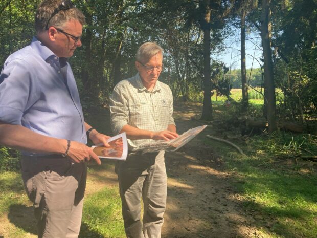 Two men in a woodland look at a map