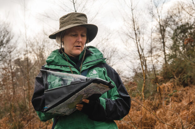 Outdoors. A person in outdoor clothing writes on a clipboard.